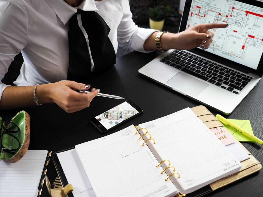 Persona trabajando Un profesional de negocios que trabaja en planes de proyectos inmobiliarios utiliza múltiples dispositivos en un entorno de oficina.